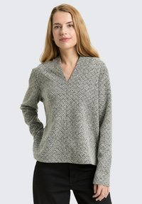 Grey and black patterned long-sleeve top with a v-neck design, made of textured fabric. Loose fit with a straight hem and minimalistic style.