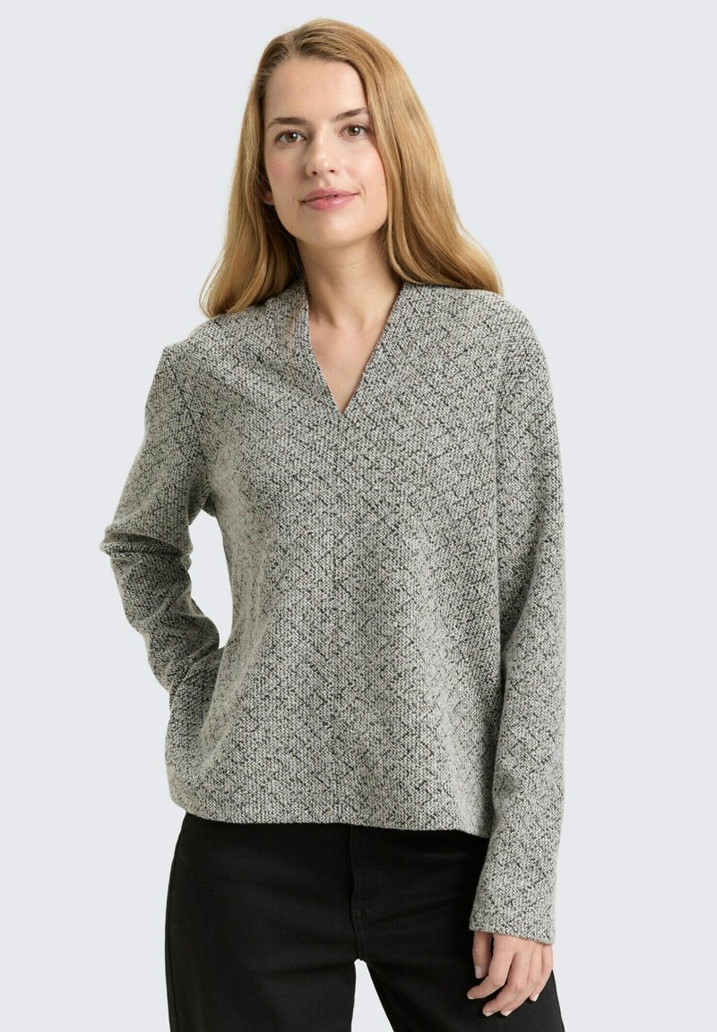 Grey and black patterned long-sleeve top with a v-neck design, made of textured fabric. Loose fit with a straight hem and minimalistic style.