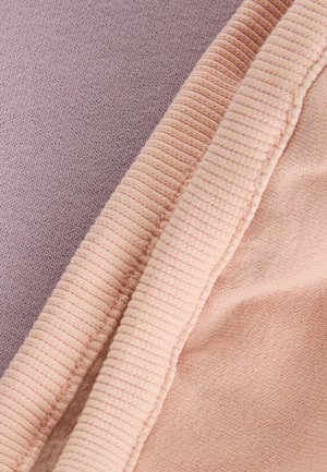 Deux échantillons de textile : un tricot lavande et un tissu côtelé pêche, mettant en valeur des textures lisses et douces avec des couleurs et des finitions contrastées.