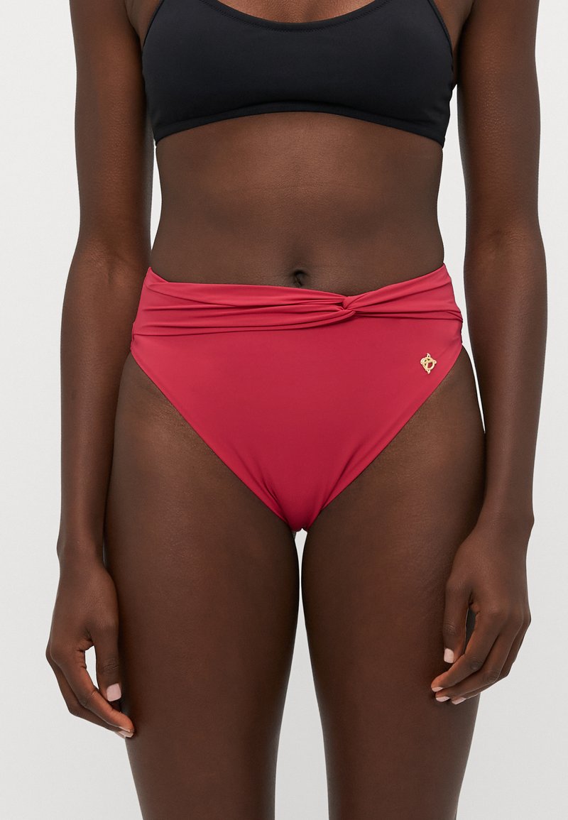 Červené bikini spodky s vysokým pásom, ktoré majú uzlový predný detail. Vyrobené z hladkého, elastického materiálu s malým zlatým logom.