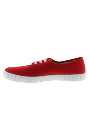 Zapatilla de tela roja con punta redondeada, suela de goma blanca y agujetas blancas. Textura suave y diseño sencillo con detalles de costura mínimos.