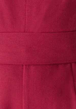 Fuchsia-Stoff mit glatter Textur, ausgestattet mit einem breiten Bund und sauberer Naht, die eine strukturierte Form in einer Nahaufnahme erzeugt.