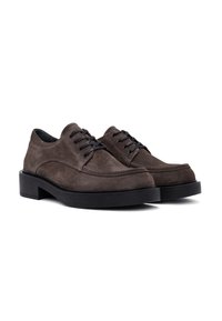 Suede brown dress shoes with black laces, rounded toes, and a thick black rubber sole. Features stitching along the sides and a smooth texture.