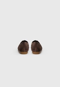 Chaussures en daim marron avec une texture lisse, profil bas, bout arrondi et un minimum de couture. Semelles en caoutchouc souple offrant une bonne adhérence.