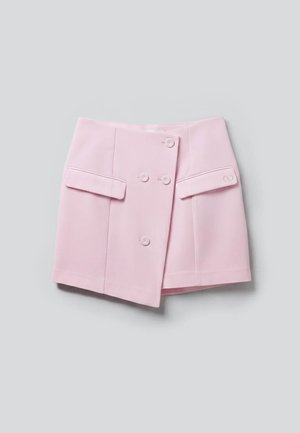 Φούστα ανοιχτό ροζ με διπλό στήθος με κουμπιά μπροστά και δύο οριζόντια τσέπες με καπάκι σε απλό γκρι φόντο.