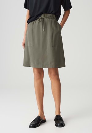Olive green skirt with an elastic waistband, two front pockets, and a knee-length cut, made from smooth, lightweight fabric.