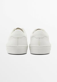 Hvide sneakers med en glat læderoverdel, afrundet tå og minimalistisk design. Har en kort hælflap og synlige syninger som accent.