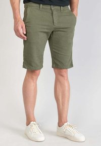 Olijfgroene cargoshorts van katoen met een rechte snit, voorzien van een knoopsluiting en zijzakken, gecombineerd met witte sneakers.