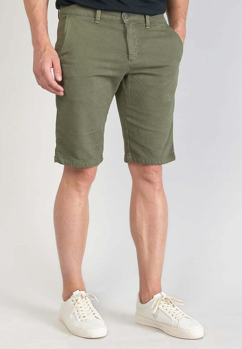 Olijfgroene cargoshorts van katoen met een rechte snit, voorzien van een knoopsluiting en zijzakken, gecombineerd met witte sneakers.