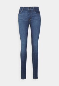 Jeans ajustados de talle alto en color azul, con bolsillos delanteros y traseros, cierre de botón y cremallera, exhibidos sobre un fondo blanco.