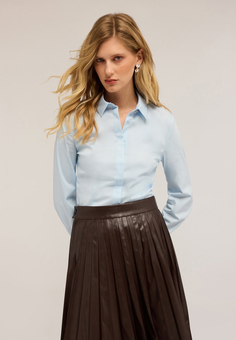 Lichtblauw button-up shirt met een kraag en lange mouwen, gecombineerd met een donkerbruine plooienrok, die een soepele textuur en een op maat gemaakte pasvorm laat zien.