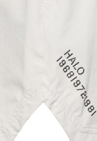 Ljust grått tyg med en slät textur, med diagonala sömmar och fettryckt text, "HALO 19681972981," på högra sidan.