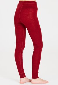 Röda leggings i mjukt tyg, med hög midja och en slät yta. De har diskreta sömdetaljer längs sidorna.