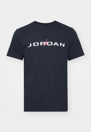 Camiseta de algodón azul marino con "JORDAN" en texto blanco y un logo Jumpman rosa en el centro. Diseño clásico de cuello redondo. Mangas cortas.