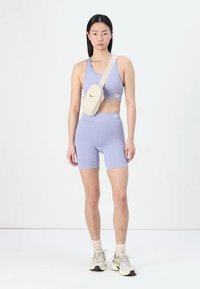 Light purple ribbed sports bra and matching shorts, paired with a beige crossbody bag. Casual athletic wear with a fitted design.