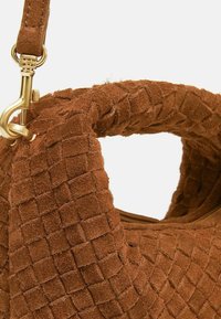 Borsa a mano in suede marrone con un motivo intrecciato testurizzato, una chiusura in hardware dorato e un design con manico arrotondato.