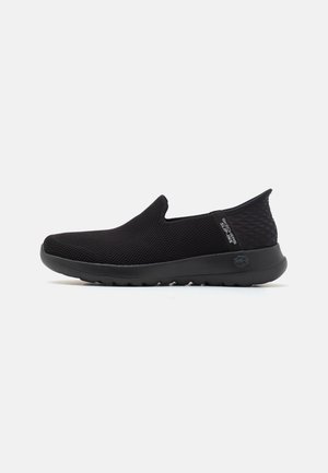 Scarpe slip-on nere con superiore in rete testurizzata, pannelli laterali elasticizzati e suola in gomma imbottita per comfort e flessibilità.