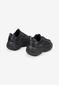 Black athletic shoes with a textured rubber sole, smooth leather and mesh upper, featuring a rounded shape and rear pull tab for easy wear.