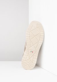 Semelle de chaussure en caoutchouc beige avec un motif de grip texturé et un logo. Bords lisses et un design en forme de diamant en évidence. Fabriqué en Italie.
