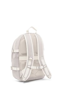 Sac à dos en tissu gris clair avec arrière en mesh rembourré, sangles réglables, poches latérales et une poignée supérieure ; présente une texture lisse et un matériel robuste.