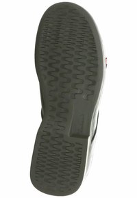 Semelle de chaussure en caoutchouc noir avec un motif texturé présentant des nervures ondulées pour une meilleure adhérence, un côté avec l'accent de la marque et un bord lisse.