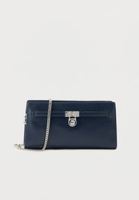 Temno modra struktura usnjena torbica z ro�čajem iz srebrne verige in okrogel srebrn zaklep na sprednji strani.