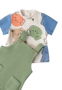 Camiseta de manga corta con estampados de animales coloridos en naranja, verde y azul; combinada con un overol texturizado verde con botones de madera.