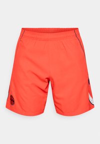 Fényes narancssárga sort elasztikus derékkal, oldalzsebekkel és fekete logóval. Sima textúra kontrasztos kék részletekkel.