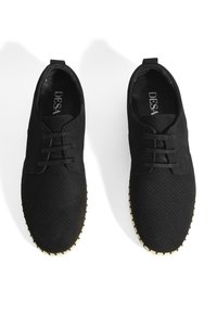 Chaussures noires à lacets avec une tige perforée, en tissu texturé, et une semelle extérieure en caoutchouc beige. Elles présentent un bout rond et un logo discret à l'intérieur.