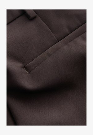 Brauner Stoff mit einer glatten, strukturierten Oberfläche und feinen Rippungen. Beinhaltet eine dezente Tasche mit einem sauberen Stichabschluss.