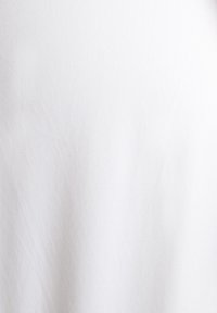 Tissu en coton blanc uni avec de subtils plis et une texture douce, éclairé uniformément sur un fond neutre.
