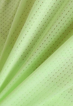 Hellgrüner Stoff mit gleichmäßig verteilten kleinen Perforationen, in weichen Falten dargestellt, die Struktur und Muster hervorheben.