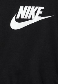 Sudadera de algodón negra con un destacado logo blanco de Nike en el centro. La tela parece suave con una textura lisa.