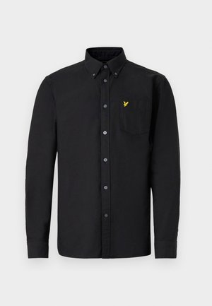 Chemise noire à manches longues avec col à boutons, poche avant et emblème jaune. Tissu en coton avec une texture lisse et coupe régulière.