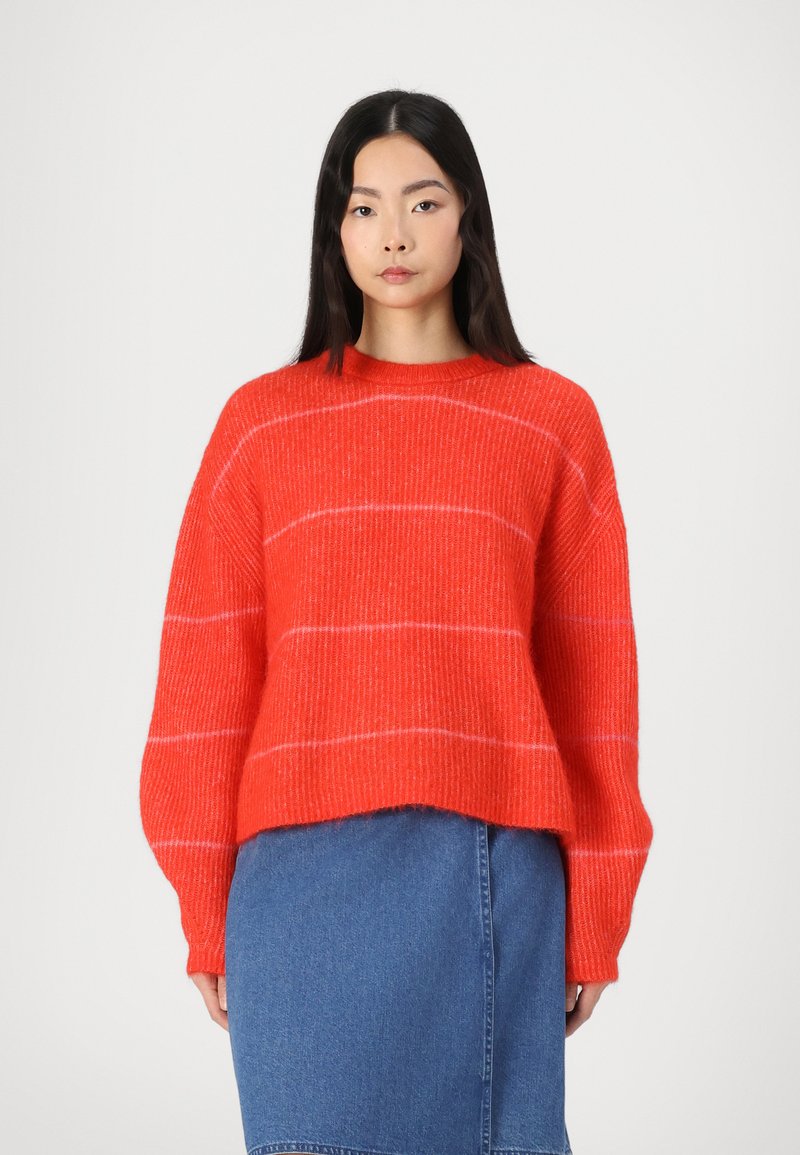 Fuzzy red knit sweater with white stripes, crew neckline, and wide sleeves, paired with a blue denim skirt. Textured, casual design.