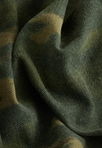 Tissu de camouflage présentant un tissage texturé dans des nuances variées de vert et de marron, avec une tomber souple et flexible et des motifs distincts.