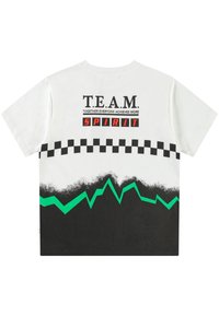 Balta marškinėliai su juoda ir žalia grafika. Užrašai „T.E.A.M.“ ir „SPIRIT“ su šachmatų ir zigzago raštu.