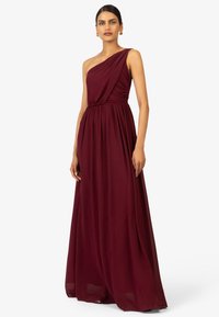 Robe de soirée bordeaux à une épaule avec un tissu drapé et une taille cintrée. Modèle long avec une texture lisse. Accents minimalistes.
