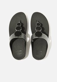 Zwarte flip-flops met een gestructureerde zool, een zilveren band en drie ronde zwarte accenten op de band. Rubber materiaal met een gladde afwerking.