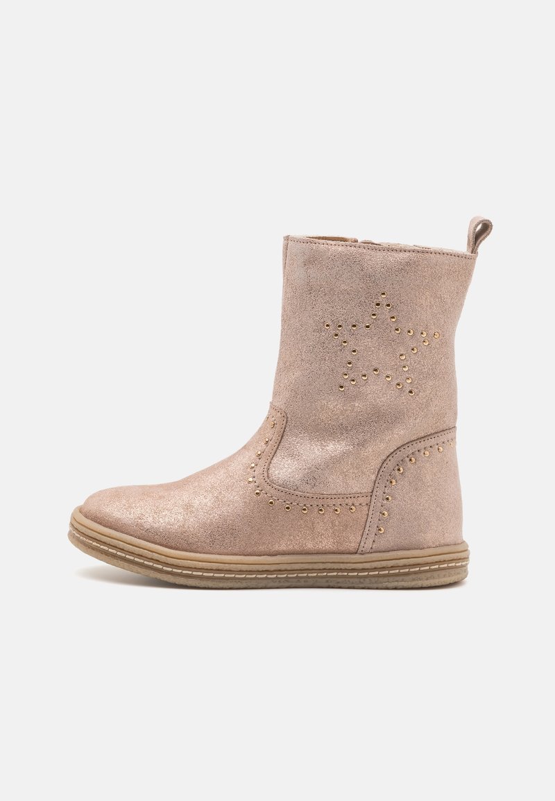 Botte mi-mollet en suédine rose clair avec semelle beige, languette de tirage et détails en clous métalliques formant une étoile sur le côté extérieur.