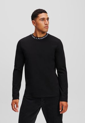 Cămașă neagră cu mânecă lungă și guler rotund, având branding alb "KARL LAGERFELD". Fabricată din material neted, asortată cu blugi negri.