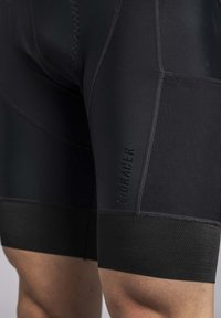 Black cycling shorts with a fitted design, textured waistbands, subtle branding, and flatlock stitching for durability.
