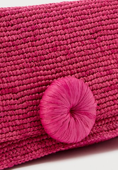 Gros plan sur un tissu tissé fuchsia texturé avec un grand bouton rond assorti cousu dessus.