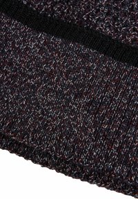 Primo piano di un tessuto a maglia texturizzato con fili misti di rosso scuro, blu e bianco e un bordo nero a coste solido.