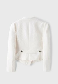 Veste blanche texturée à manches longues avec une bande dans le dos retenue par deux boutons, présentée sur un fond gris clair uni.