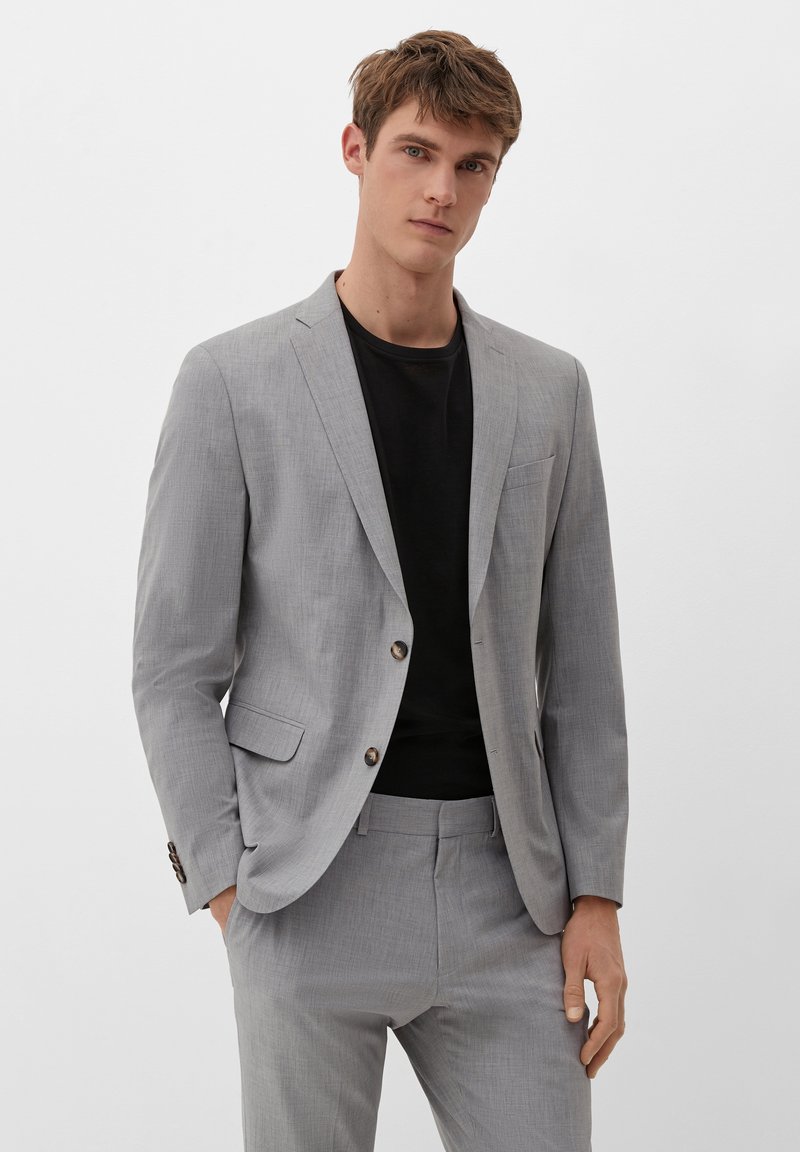 Hellgrauer Blazer aus strukturiertem Stoff mit einem Ein-Knopf-Verschluss, schmalen Revers und einer Brusttasche, kombiniert mit einem schwarzen Hemd darunter.