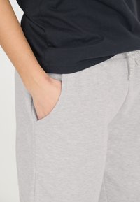 Grå sweatpants med sidofickor och dragsko i midjan, tillsammans med en svart t-shirt, som visar en mjuk, avslappnad textilfinish.