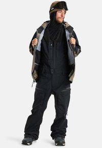 Czarny wodoodporny kombinezon śniegowy z zamkiem błyskawicznym z przodu, wieloma kieszeniami i kurtką w wzór moro. Posiada ocieplaną podszewkę i buty narciarskie.