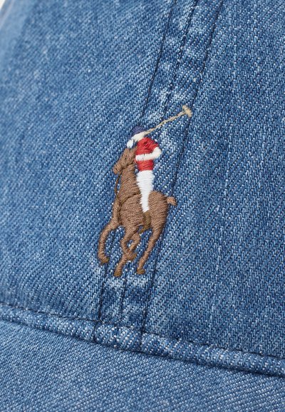 Embroidered polo player in red, white, and blue riding a brown horse, stitched on blue denim fabric.