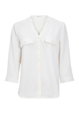 Blusa bianca, strutturata, con scollo a V, maniche a tre quarti e due tasche frontali. Chiusura centrale con bottoni. Tessuto morbido.
